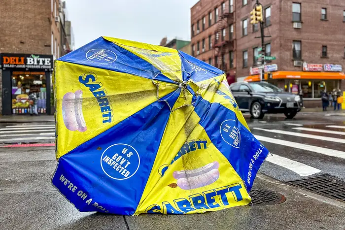 a knocked over Sabrett hot dog umbrella on a rainy day